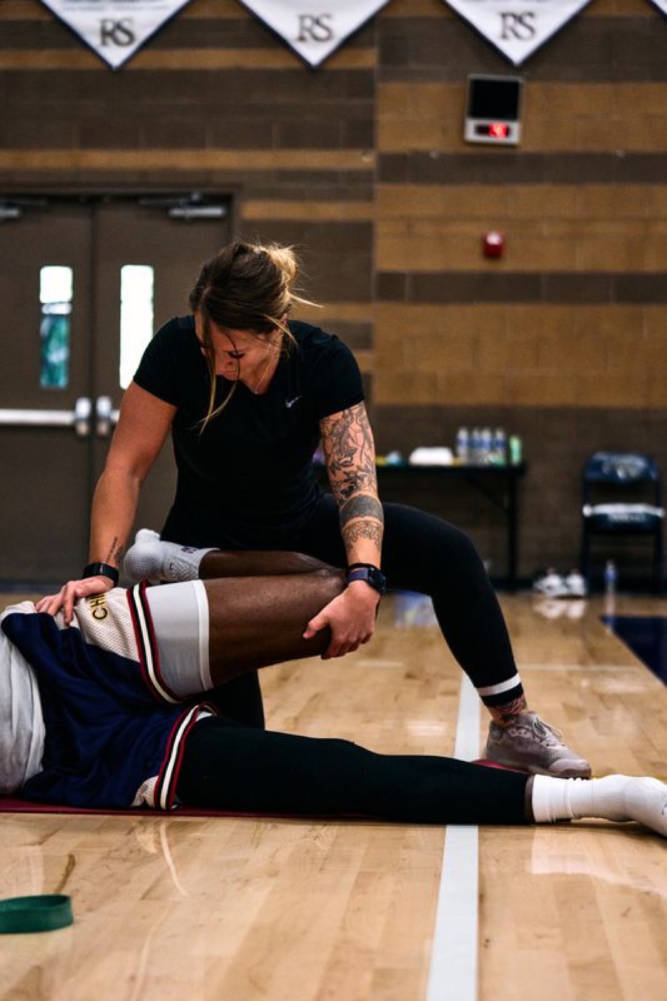 Alex Hubelbank treating a player on a basketball court.